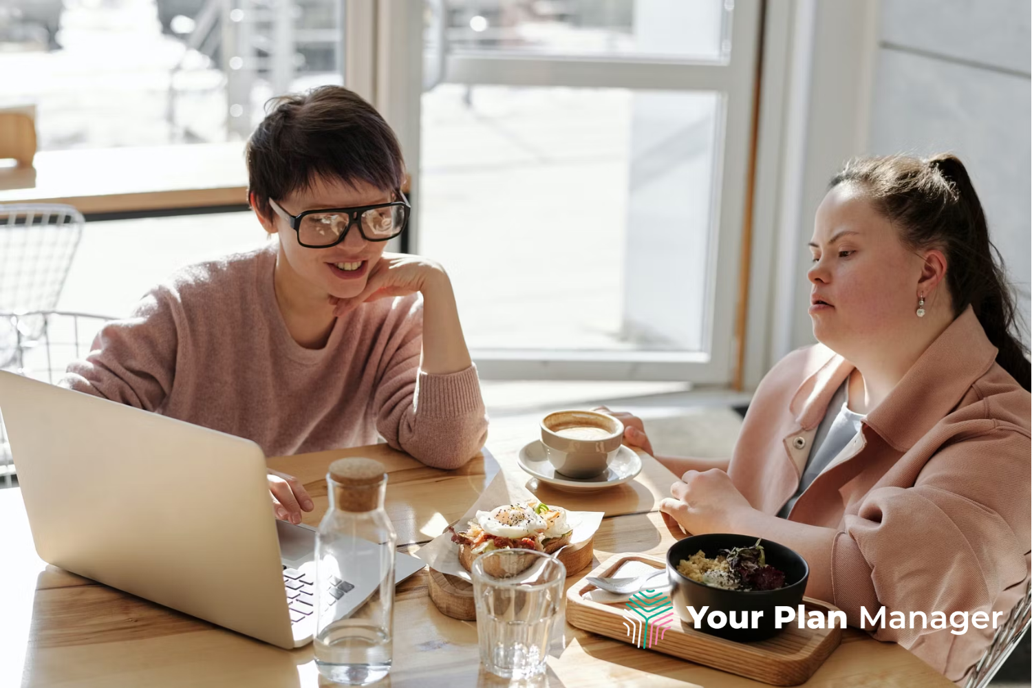 Two women working at a cafe discussing NDIS Plan Management.